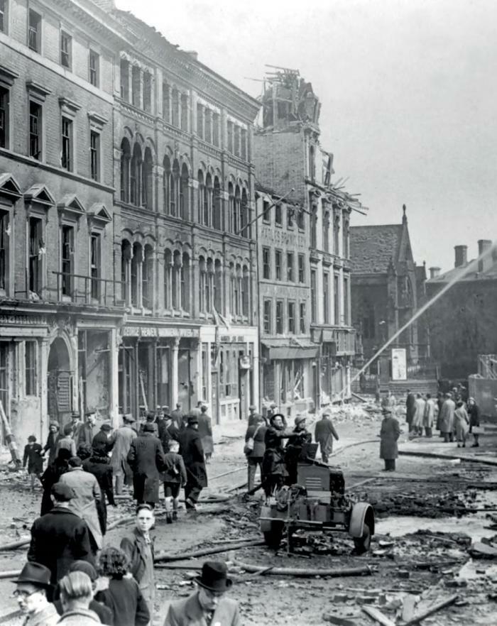 A black and white photograph of firemen putting out flames on a damaged building