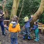 Three children playing around trees