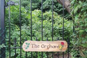 A black metal gate with a sign for 'The Orchard'